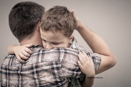 44124466 - sad son hugging his dad near wall at the day time